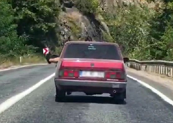 Ayaklarını camdan sarkıtarak trafiği tehlikeye attı